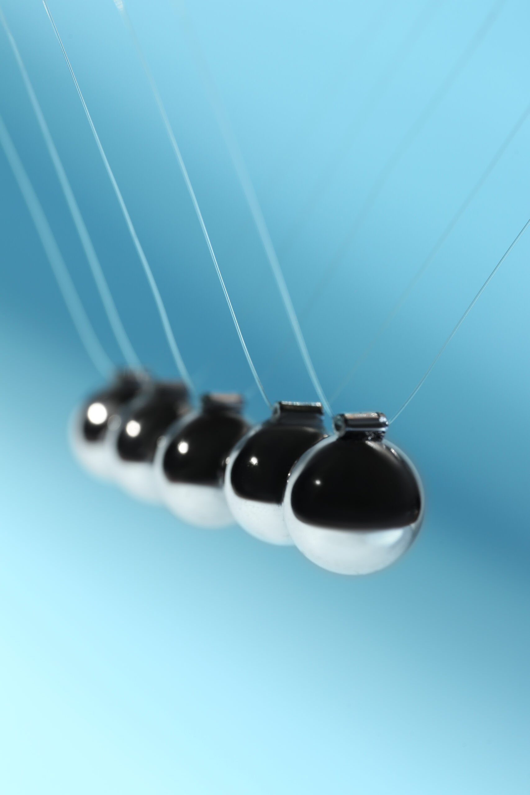 Newton's cradle on light blue background, used to demonstrate the physics law of energy conservation. It also symbolizes consistency one of the fundamental mind shifts to to become an entreprenueur.